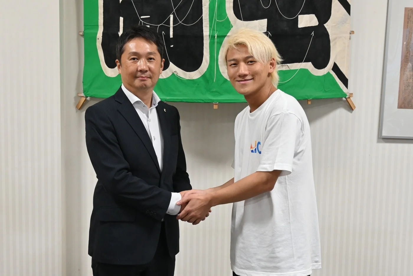 埼玉新聞社様とAI coachの業務提携に関する公開写真。二人が握手している。